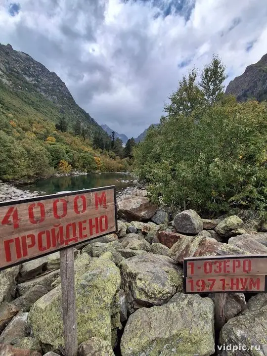 Sign by mountain river. A sign with the inscription "4000 m пройдено" is installed by a mountain river.