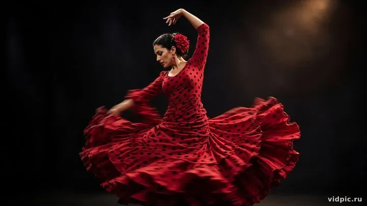 A dancer in a red dress under dramatic stage light.