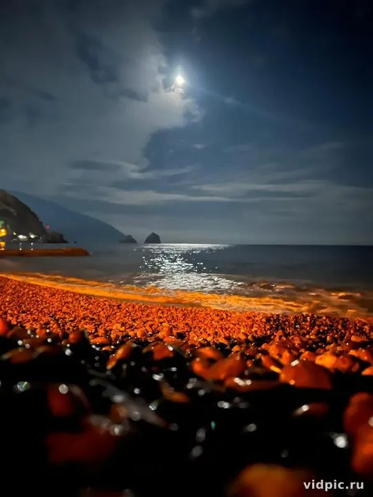 A night scene of a rocky beach illuminated by moonlight. Perfect for creating a sense of calm and mystery.