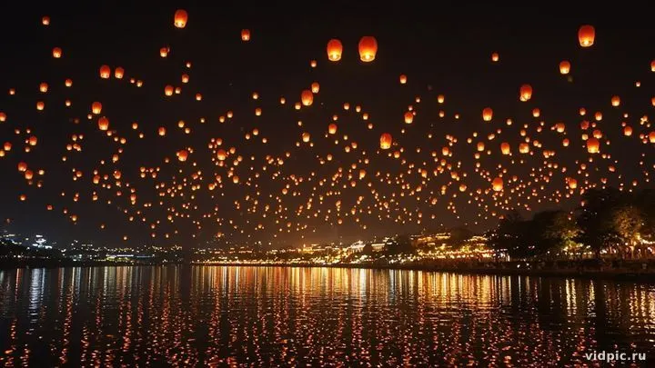Hundreds of glowing lanterns rising into the night sky.