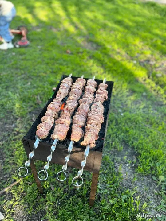Lamb kebabs on coals. Lamb kebabs are grilling on a metal grill over coals.